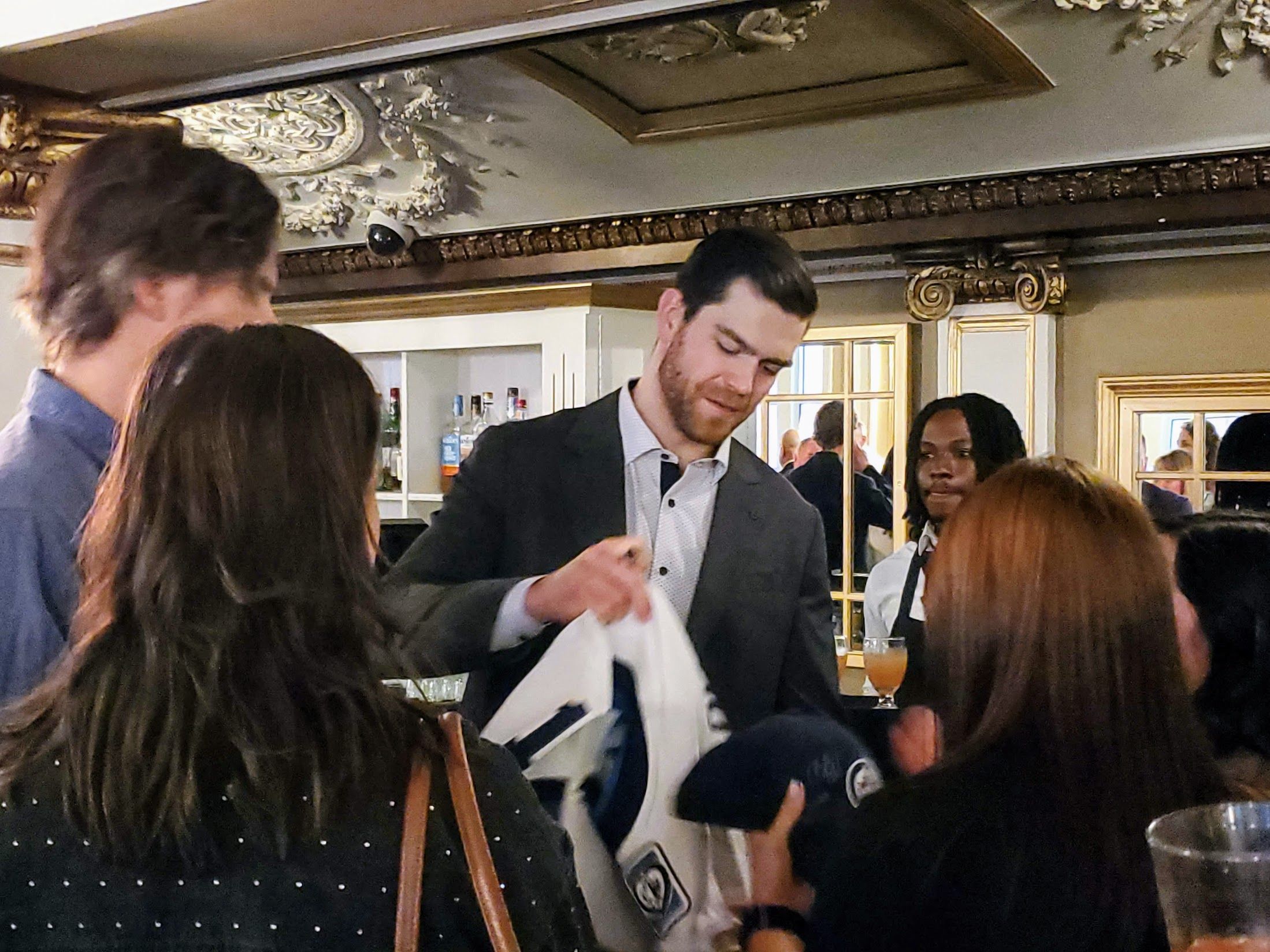 A man uses a marker to sign an autograph on a hockey jersey